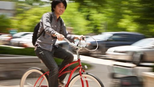 学生在外面骑着红色的自行车